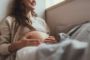 Glad future mom tuching her tummy and smiling