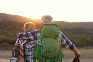 Hugged mature couple with packpacks looking at sunset